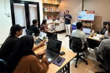 Fasilitator AI University mendampingi peserta training dengan laptop